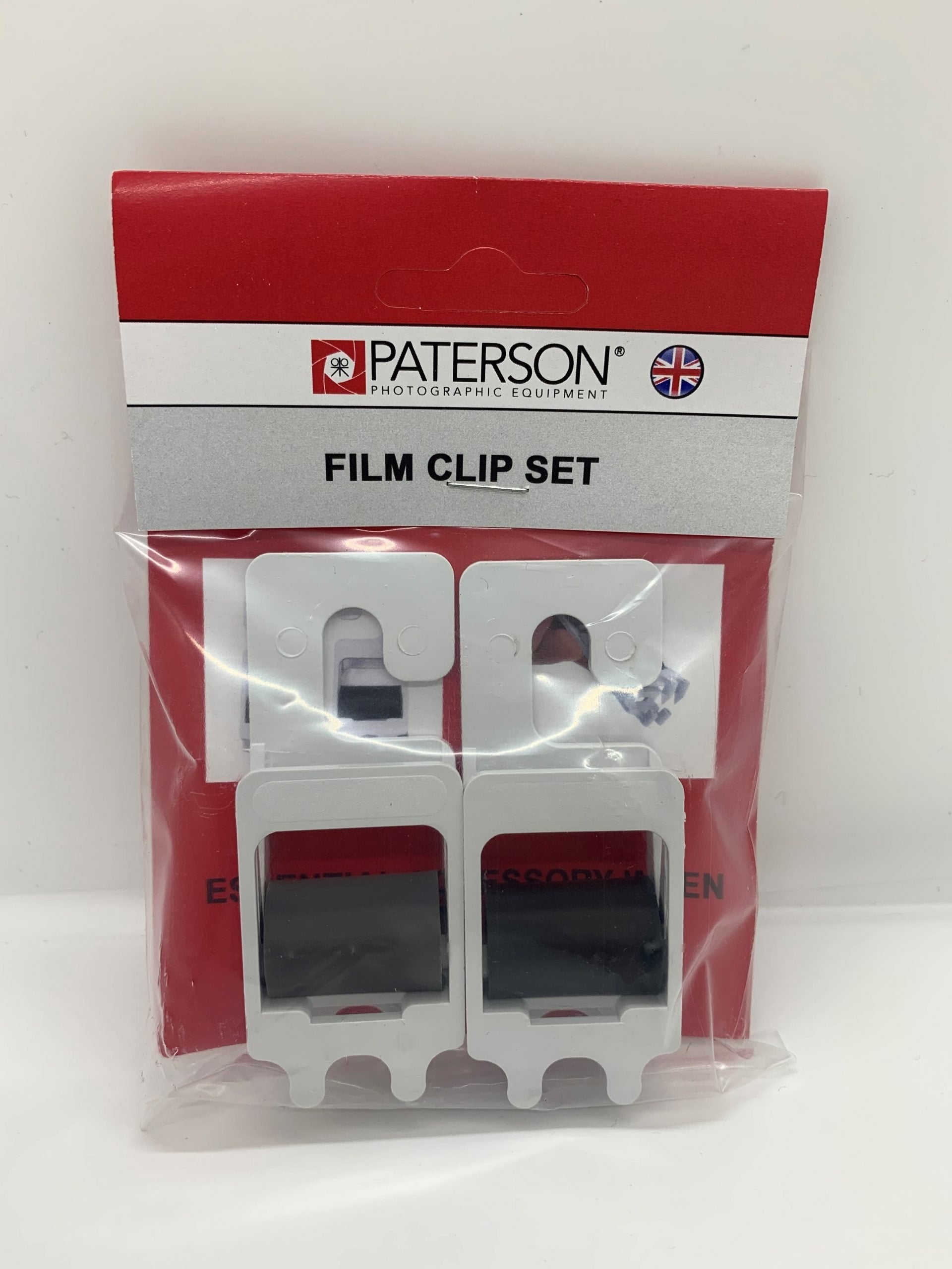 Film development kit with two spring-loaded clips. Spikes grip film for straight drying. Weighted clip maintains alignment.